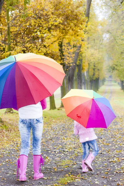 Moeder en haar dochter met paraplu's in herfst steegje — Stockfoto