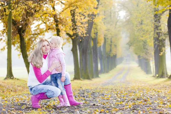 Anya és lánya a napernyők őszi sikátorban — Stock Fotó