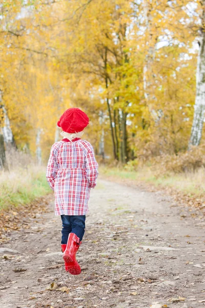 少女がゴムを着て紅葉の路地でブーツします。 — ストック写真