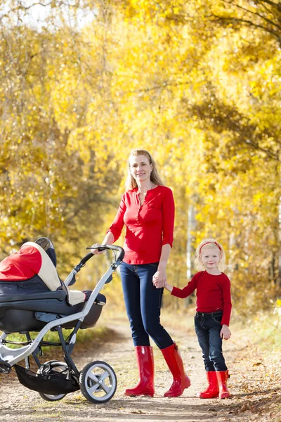 Mutter und Tochter mit Kinderwagen auf Spaziergang in der Herbstgasse — Stockfoto