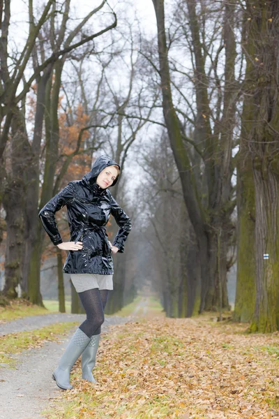 Kvinna som bär gummi stövlar i höstlig gränd — Stockfoto