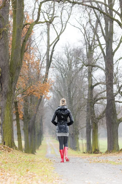 Frau trägt Gummistiefel in herbstlicher Gasse — Stockfoto