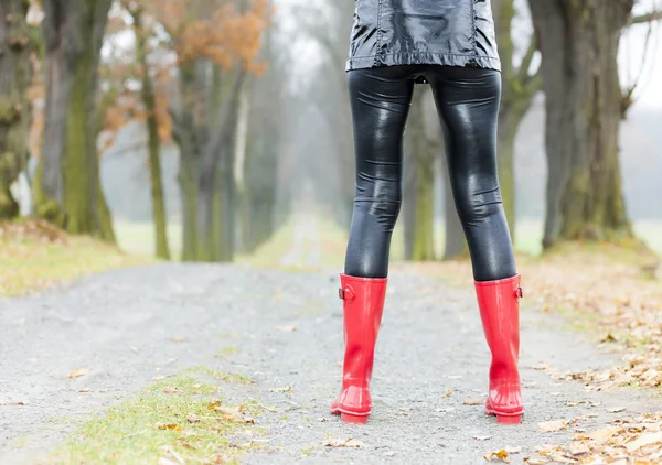 Mulher usando botas de borracha em beco outonal — Fotografia de Stock