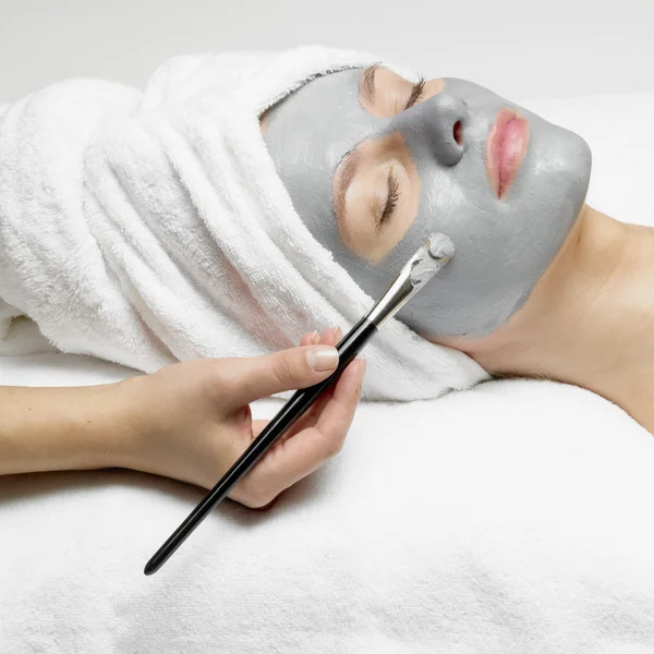 Application of a cosmetic mask on the face of young woman at the beautician Stock Image