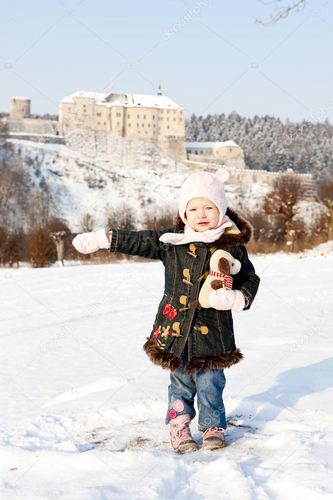 Standing little girl and Cesky Sternberk Castle in winter at bac