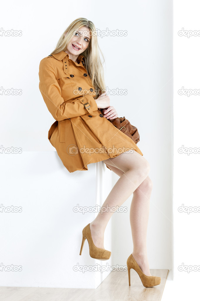 Sitting woman wearing brown coat and pumps with a handbag