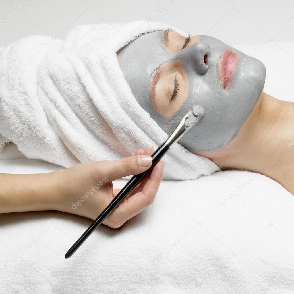 Application of a cosmetic mask on the face of young woman at the beautician