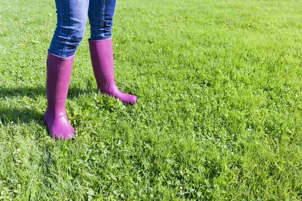 Detail of woman wearing rubber boots on spring meadow — Stock Photo, Image