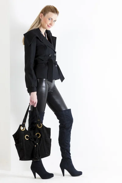Mujer de pie vestida de negro con un bolso —  Fotos de Stock