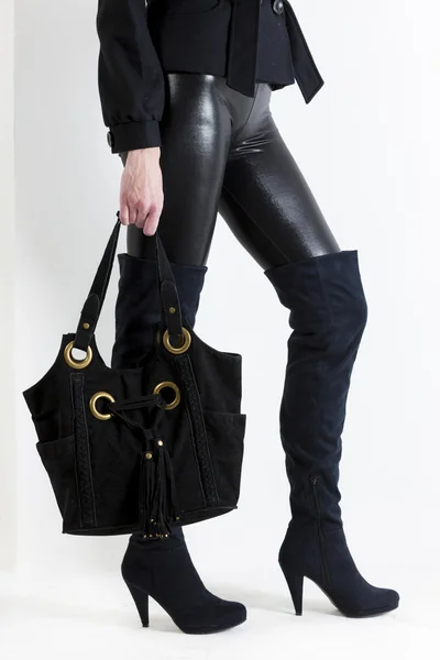 Λεπτομέρεια της όρθιας γυναικείας φορώντας μαύρες μπότες με μια τσάντα — Φωτογραφία Αρχείου