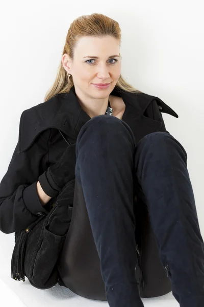 Retrato de una mujer sentada vestida de negro y botas — Foto de Stock