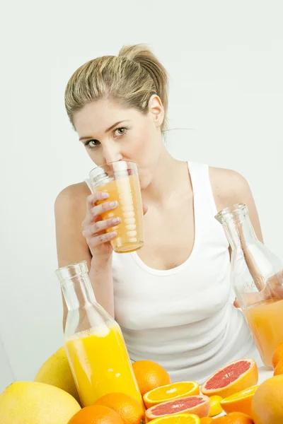Portrait of young woman with citrus fruit and orange juice — Stock Photo, Image