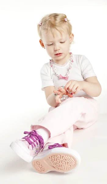 Sitting little girl wearing necklace — Stock Photo, Image