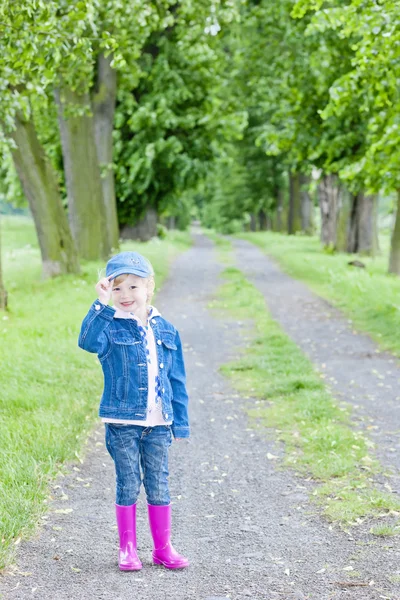 Kis lány visel gumi csizma tavaszi sikátorban — Stock Fotó