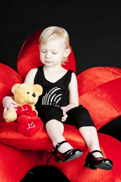 Petite fille avec un ours en peluche assis sur un fauteuil rouge — Photo