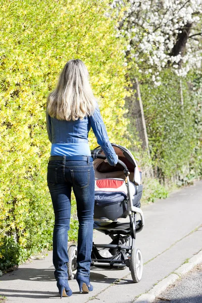 Kvinna med barnvagn på vår promenad — Stockfoto