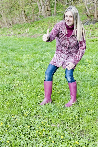 Femme portant des bottes en caoutchouc sur prairie de printemps — Photo