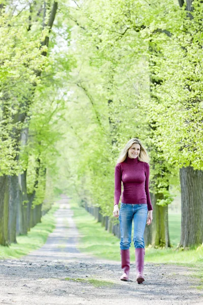 Frau in Gummistiefeln läuft in Frühlingsgasse — Stockfoto