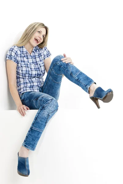 Sittande kvinna klädd i jeans och jeans träskor — Stockfoto