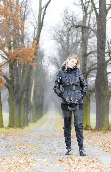 Frau trägt schwarze Kleidung und Stiefel in der herbstlichen Gasse — Stockfoto