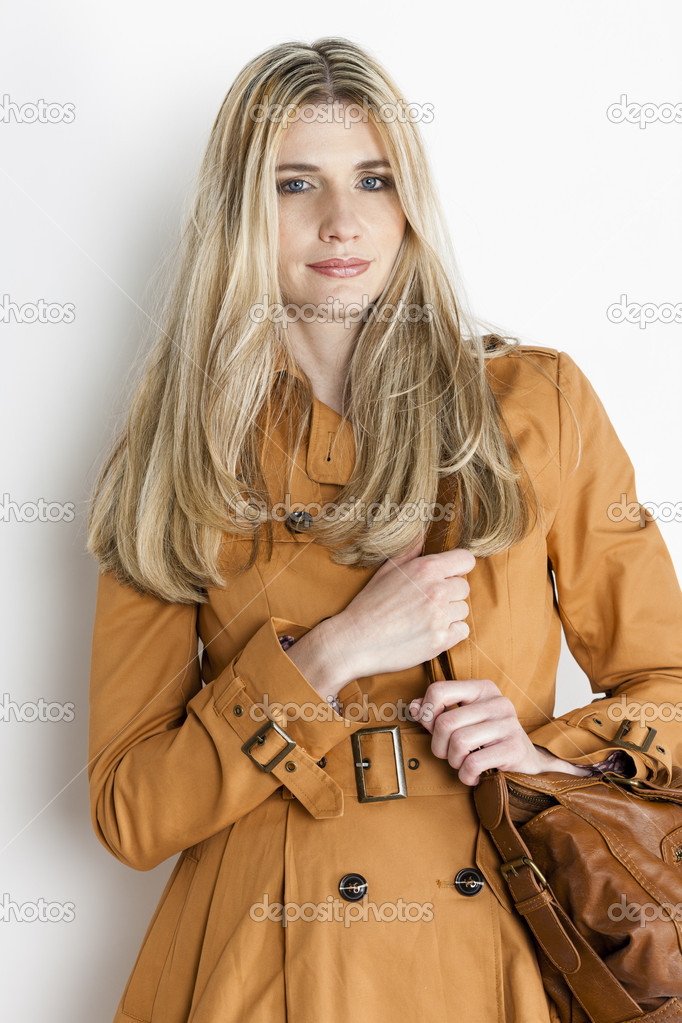portrait of standing woman wearing brown coat with a handbag