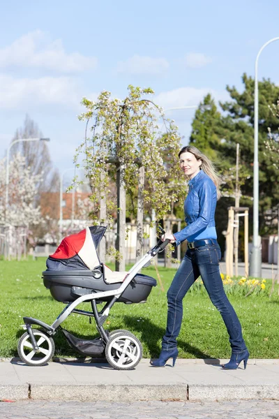 Donna con una carrozzina in primavera a piedi — Foto Stock