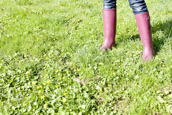 Détail de la femme portant des bottes en caoutchouc sur prairie de printemps — Photo