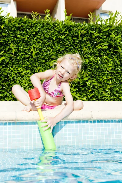 Маленькая девочка с распылителем воды у бассейна — стоковое фото