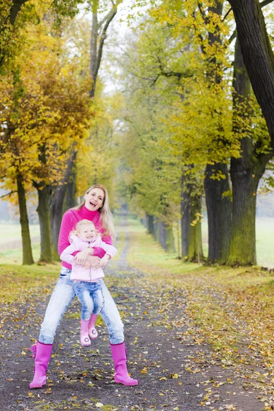 Mamma med sin dotter i höstlig gränd — Stockfoto