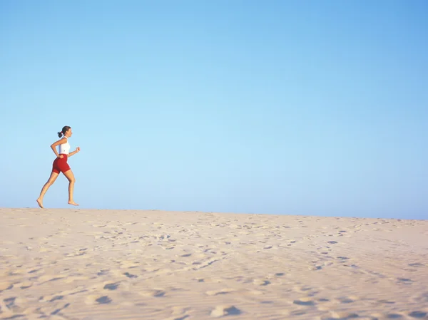 Frau joggt am Strand. — Stockfoto