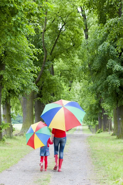 Anya és lánya esernyővel a tavaszi sikátorban — Stock Fotó
