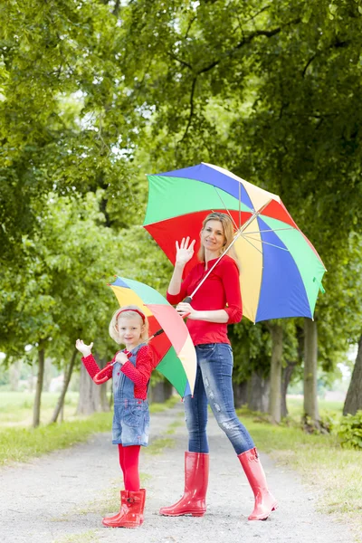 Anne ve kızı bahar sokağında şemsiyeli. — Stok fotoğraf