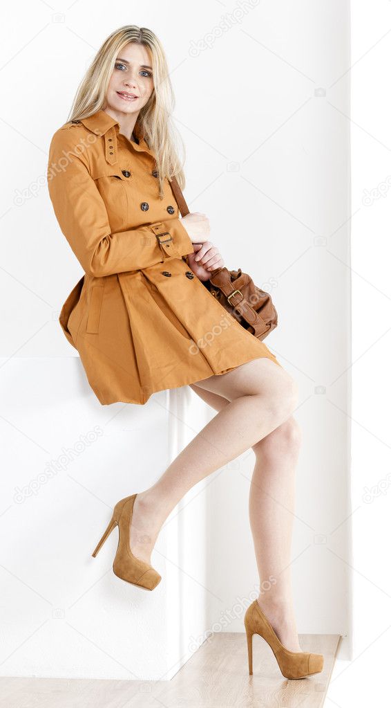 sitting woman wearing brown coat and pumps with a handbag