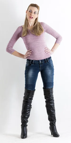 Стоячая женщина в джинсах и черных сапогах — стоковое фото