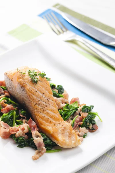 Salmon fillet with warm spinach and bacon salad — Stock Photo, Image