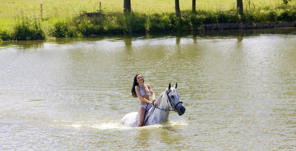Equestrian on horseback riding through water Stock Photo by ©phb.cz