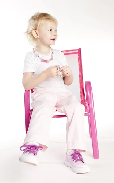 Bambina che indossa una collana seduta sulla sedia — Foto Stock