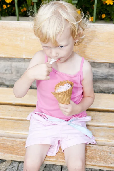 Petite fille avec de la crème glacée assis sur le banc — Photo