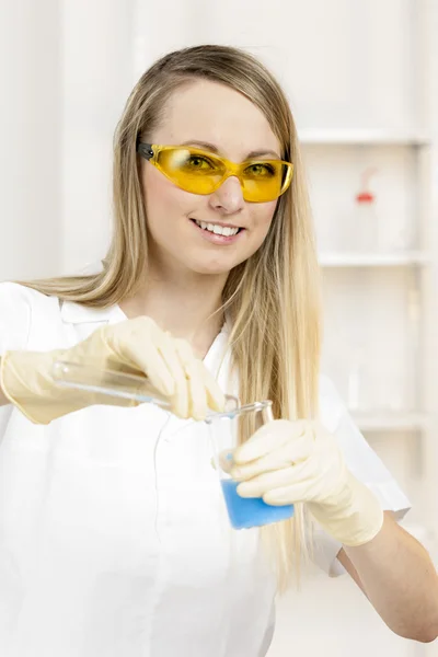 Mujer joven haciendo experimento en laboratorio —  Fotos de Stock