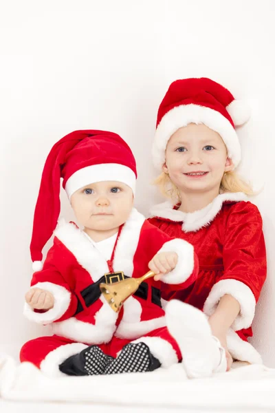 Two little girls as Santa Clauses with a bell Stock Photo