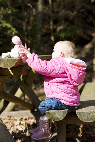 Liten flicka sitter på bänken — Stockfoto