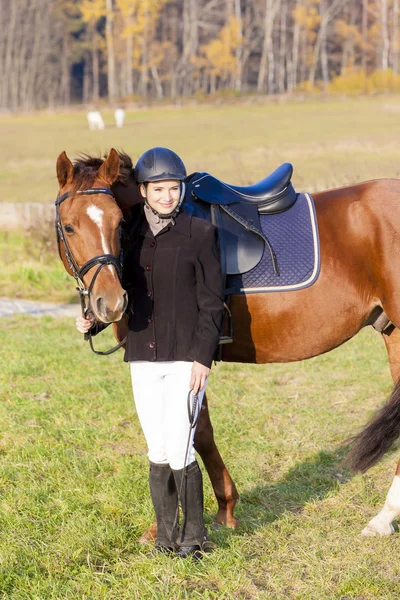 Ridsport med hennes häst på äng — Stockfoto
