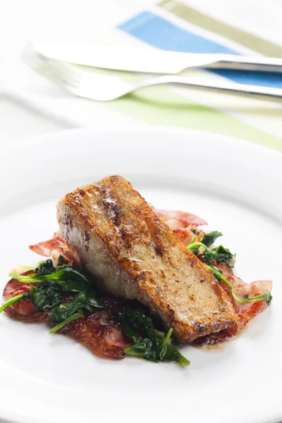 Tilapia fillet with warm spinach and bacon salad — Stock Photo, Image