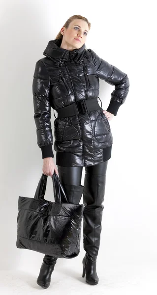 Mujer de pie vistiendo ropa negra sosteniendo un bolso — Foto de Stock