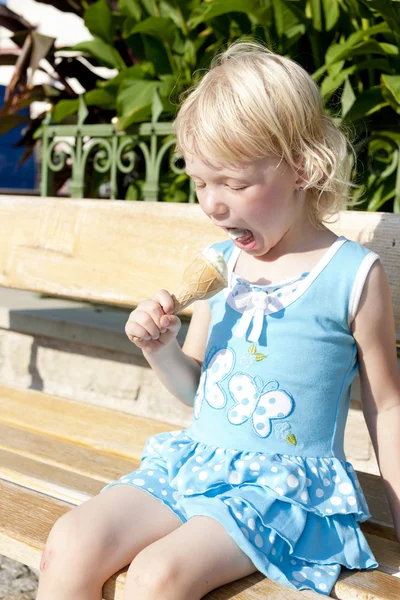 Kleines Mädchen mit Eis auf Bank sitzend — Stockfoto