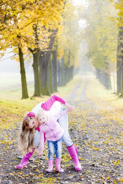 Moeder met haar dochter in herfst steegje — Stockfoto