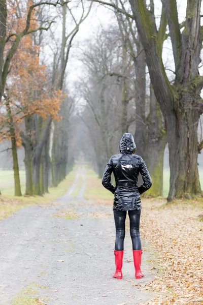 Woman wearing rubber boots in autumnal alley — Stock Photo, Image