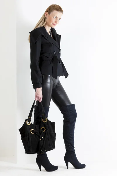 Mulher de pé vestindo roupas pretas com uma bolsa — Fotografia de Stock