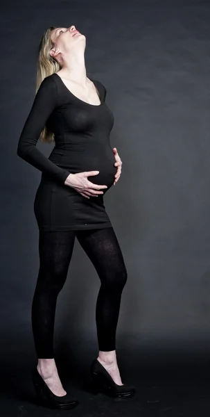 Pregnant woman wearing black clothes and pumps — Stock Photo, Image