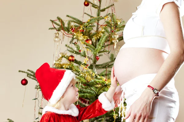 Retrato de menina e sua mãe grávida por natal tre — Fotografia de Stock